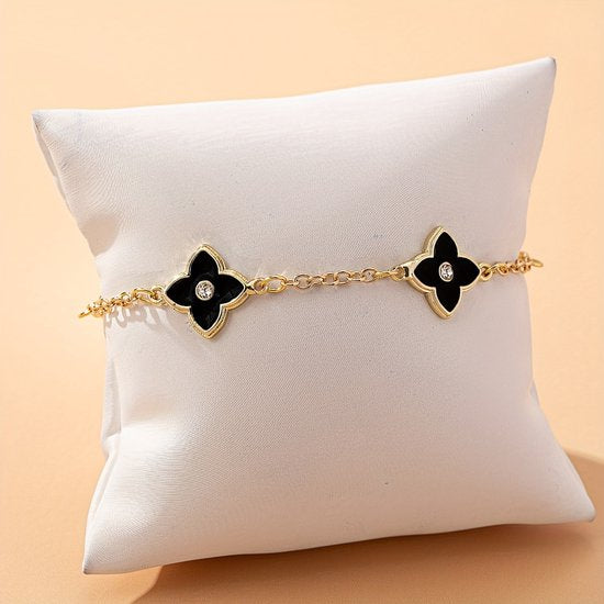 Sjika - Gold plated armband met zwarte klaver bloemen – Luxe damesarmband met kristalaccent – Trendy & Elegant sieraad – Perfect cadeau voor haar
