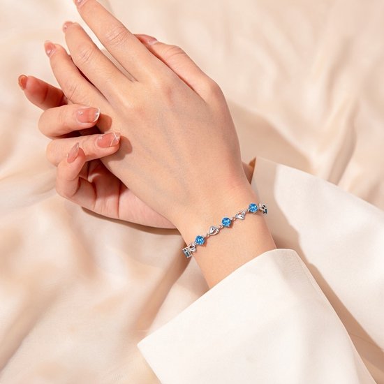 Sjika - Zilverkleurige armband met blauwe kristallen & hartjes – Luxe damesarmband – Elegant & romantisch design – Perfect cadeau voor haar