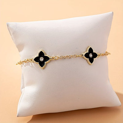 Sjika - Gold plated armband met zwarte klaver bloemen – Luxe damesarmband met kristalaccent – Trendy & Elegant sieraad – Perfect cadeau voor haar