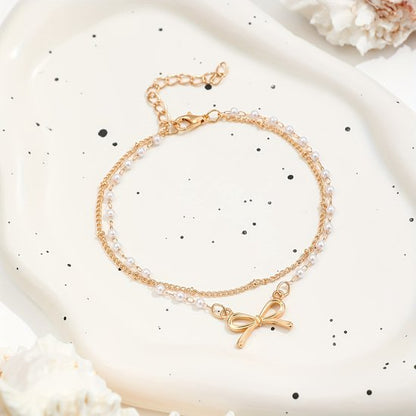Sjika - Enkelbandje Dames Goudkleurig met Strik & Parels – Dubbele Enkelband – Trendy Zomer Enkelketting – Boho Voetsieraad - Cadeau voor haar