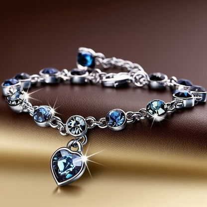 Sjika - Zilverkleurige armband met blauwe kristallen & hart hanger – Luxe damesarmband – Elegant & romantisch design – Perfect cadeau voor haar