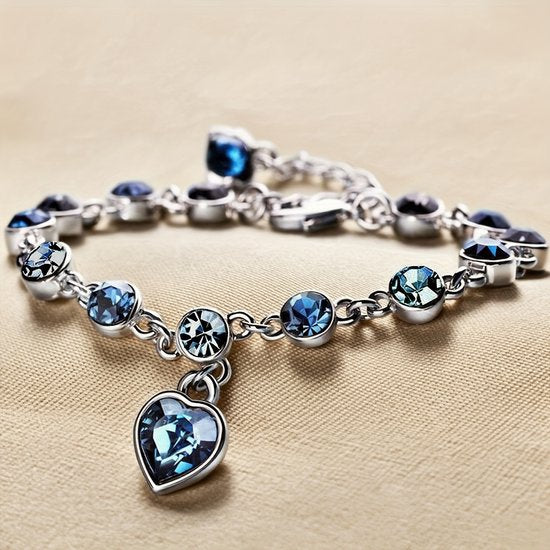 Sjika - Zilverkleurige armband met blauwe kristallen & hart hanger – Luxe damesarmband – Elegant & romantisch design – Perfect cadeau voor haar