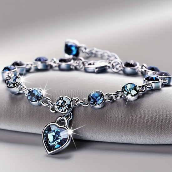Sjika - Zilverkleurige armband met blauwe kristallen & hart hanger – Luxe damesarmband – Elegant & romantisch design – Perfect cadeau voor haar