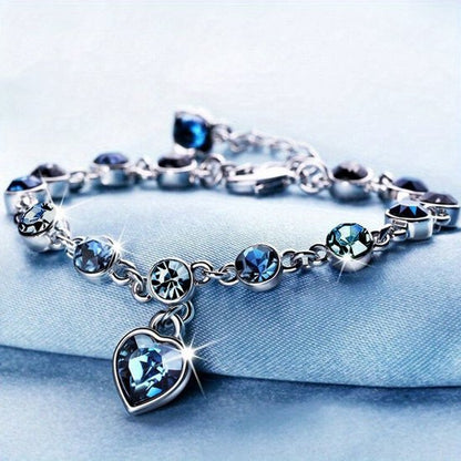 Sjika - Zilverkleurige armband met blauwe kristallen & hart hanger – Luxe damesarmband – Elegant & romantisch design – Perfect cadeau voor haar